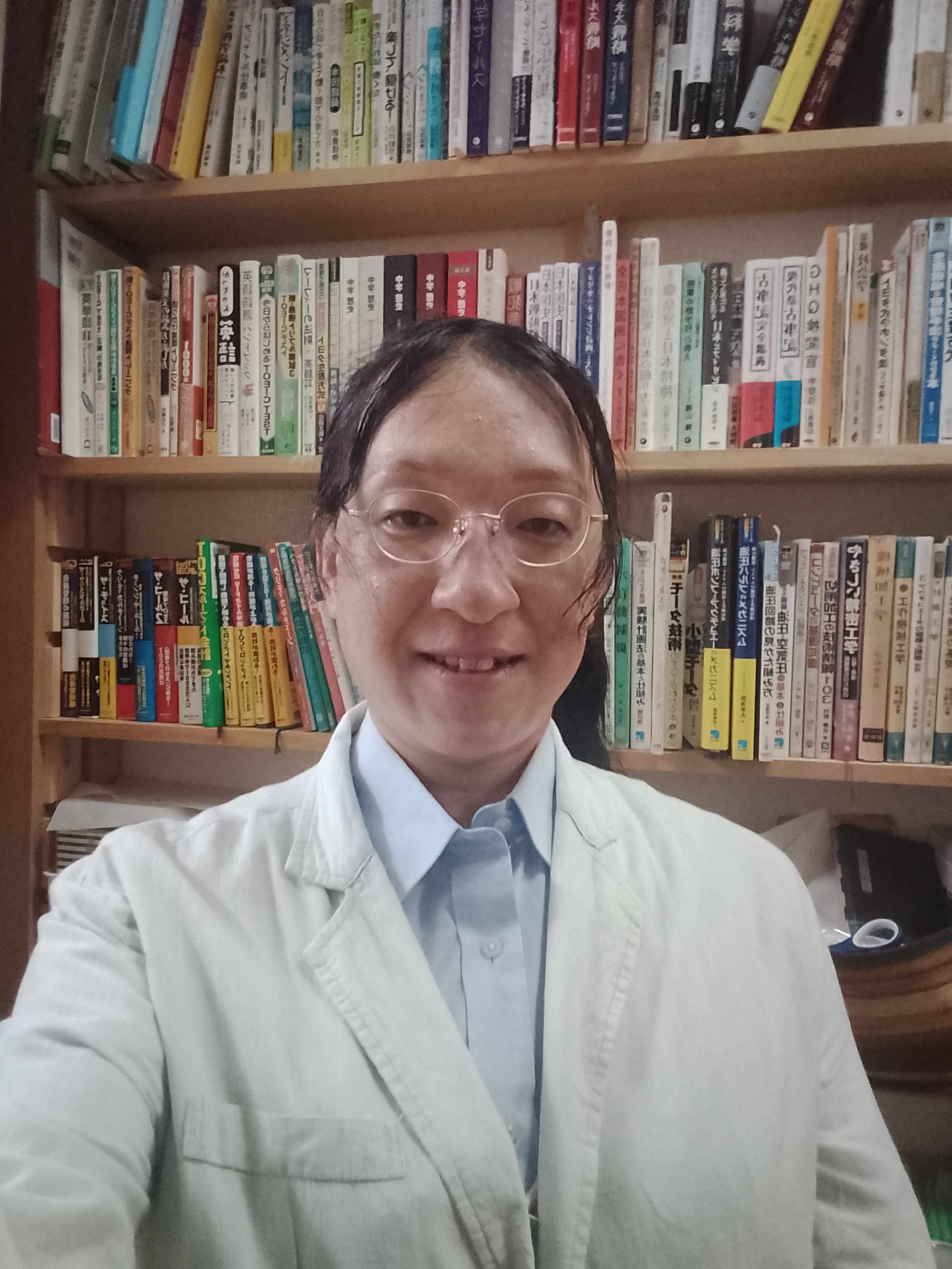 本棚の前に立つSo more sun主催・有田隆一
